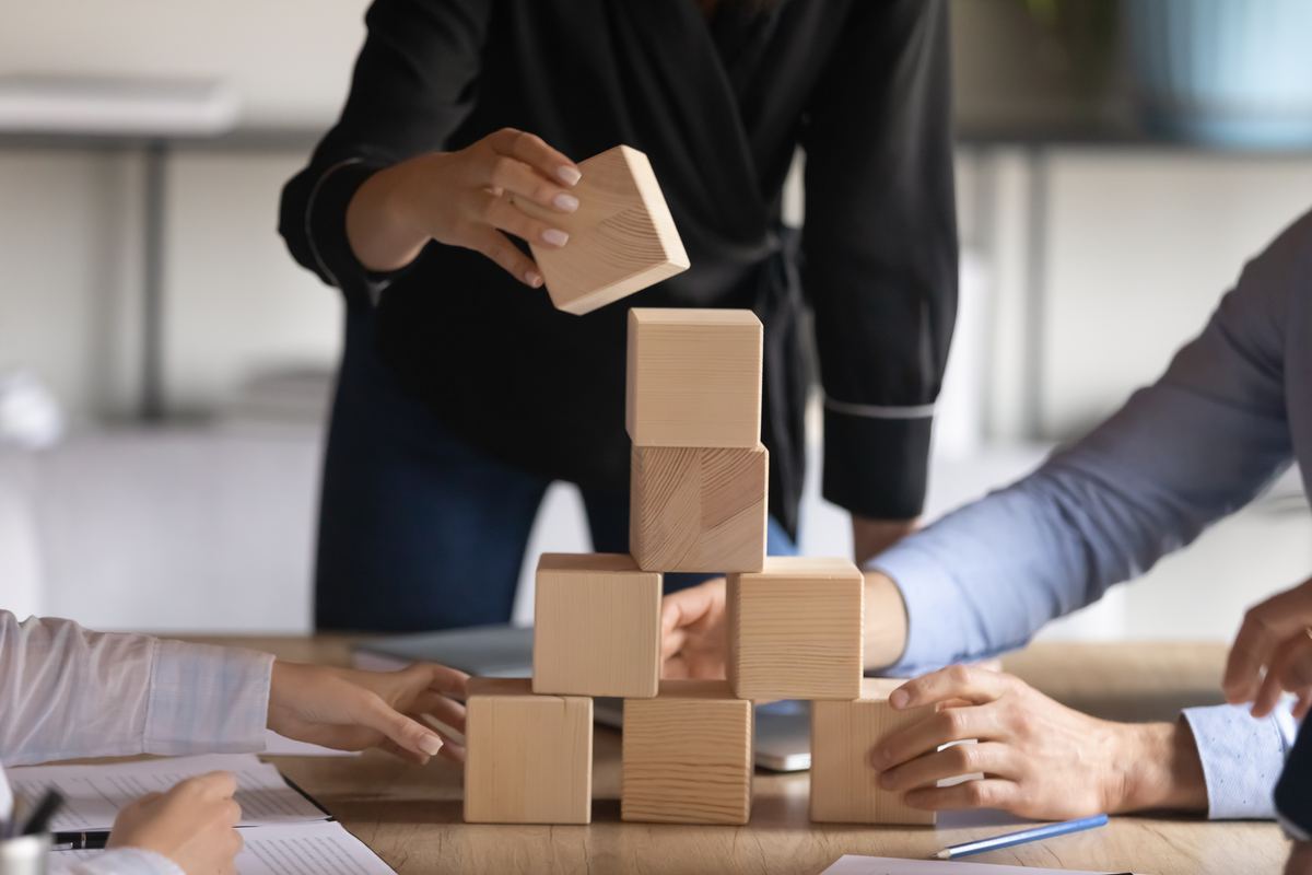 Vier mensen bouwen samen aan een constructie van houten blokken